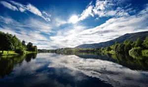 a lake with trees and clouds