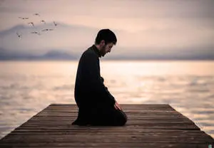 رجل يصلي راكعًا على الرصيف