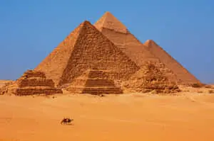 Majestic view of the Pyramids of Giza bathed in a rust-colored hue.